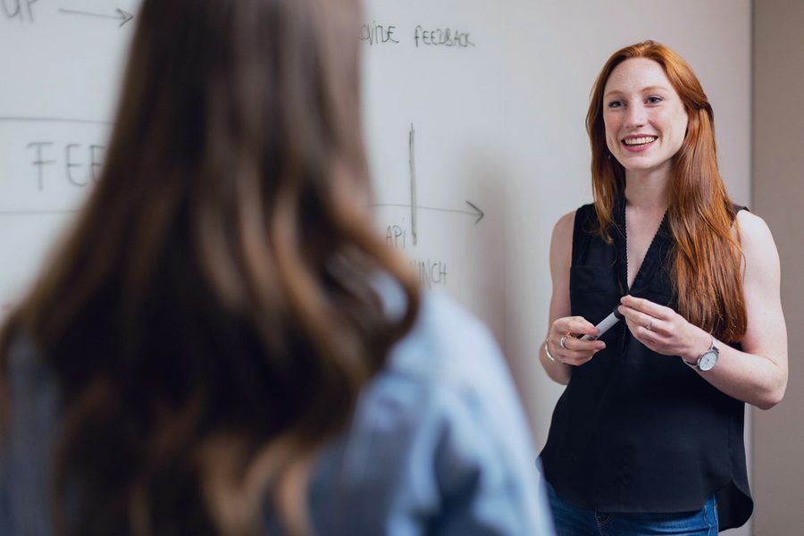 An educator mapping a feedback program on a whiteboard with a colleague