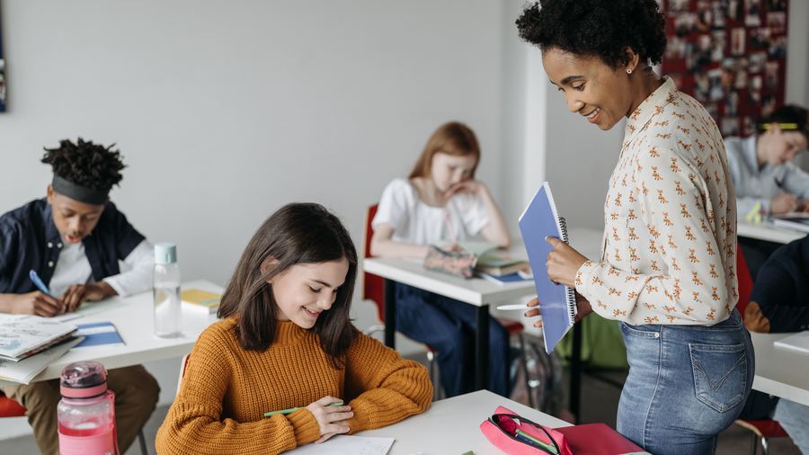A teacher helping a student with classwork in a classroom