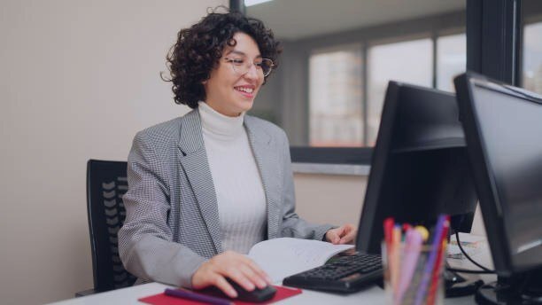 An educator working at a computer, reviewing notes